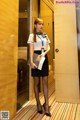 A woman in a white shirt and black skirt standing in an elevator.