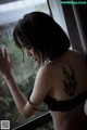 A woman with a tattoo on her back looking out a window.