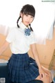 A woman in a school uniform sitting on a couch.
