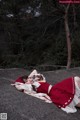 A woman in a red and white dress laying on a rock.