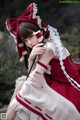 A woman in a red and white dress holding a stick.