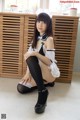 A woman in a maid outfit sitting on the floor.